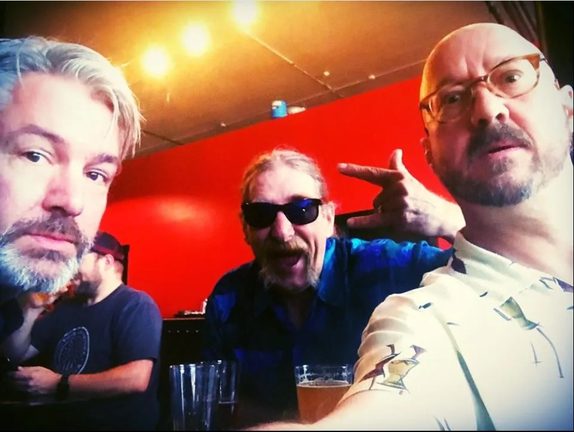 Three band members of Mr. Blackwatch posing together for a selfie at a bar.