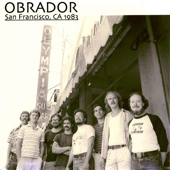 San Francisco, CA 1983 — cover art. Black-and-white photo of the band standing in a row on a sidewalk in front of the Olympia Surplus Market awning, one member wearing a shirt printed with the album title.